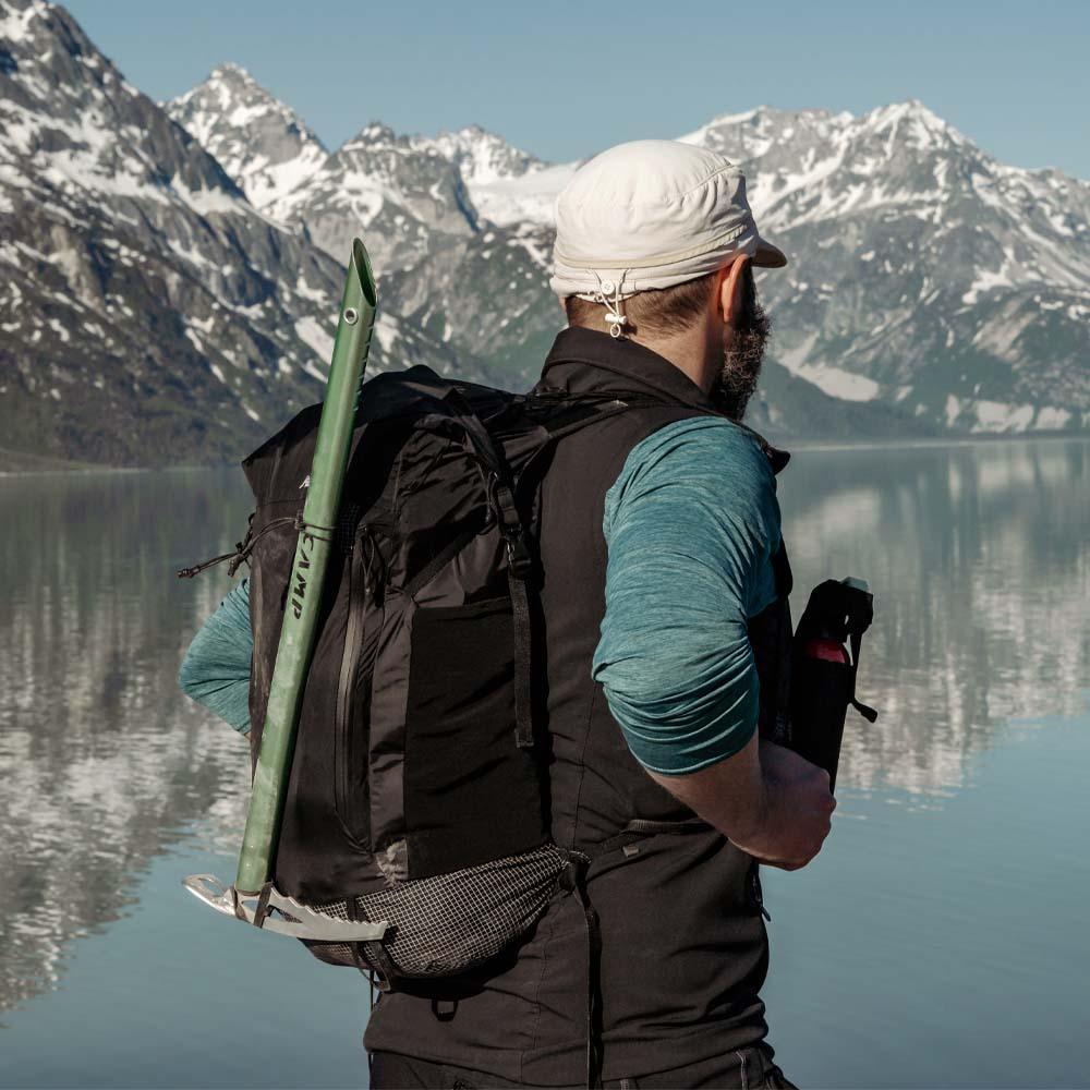 a man with a backpack infront of a mountain and lake
