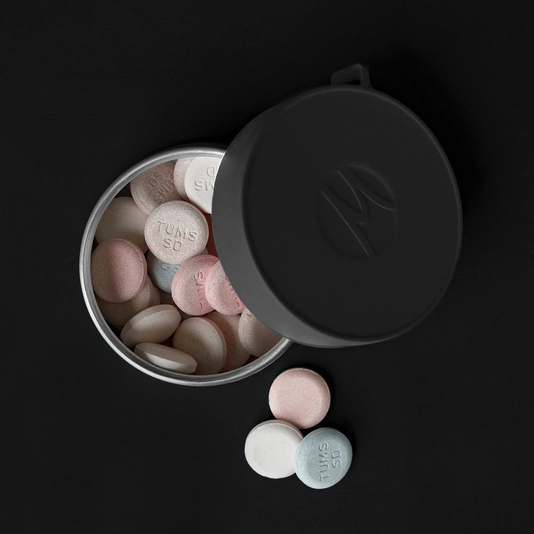Large canister full of antacids on black background