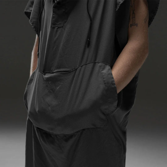 man in front of gray background with both hands in charcoal poncho kangaroo pocket