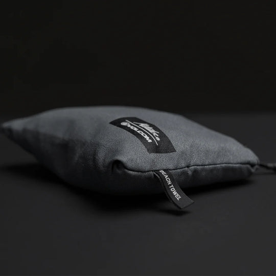 packed up charcoal beach towel shot on dark gray background