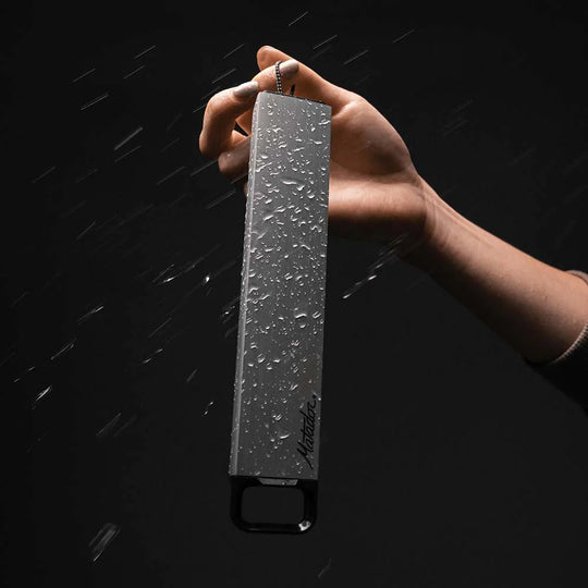 Hand holding pill canister, covered in beaded water, on black background