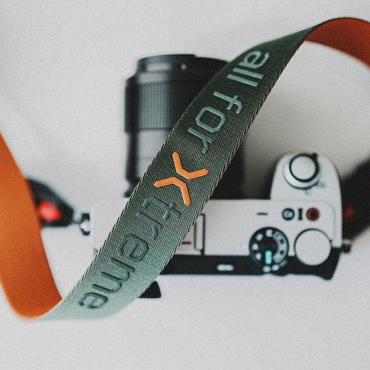 Camera strap on a blurred background of a camera and lens.