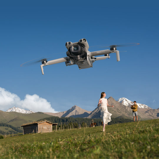 Drone flying over a scenic landscape with mountains and a person in a dress.