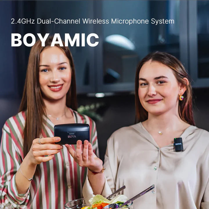 Two women with wireless microphones and a 2.4GHz Dual-Channel Wireless Microphone System by BOYAMIC.