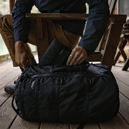 Man outside, pulling Laptop base layer from bag