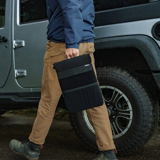 Man walking outside holding Laptop base layer by cary handle