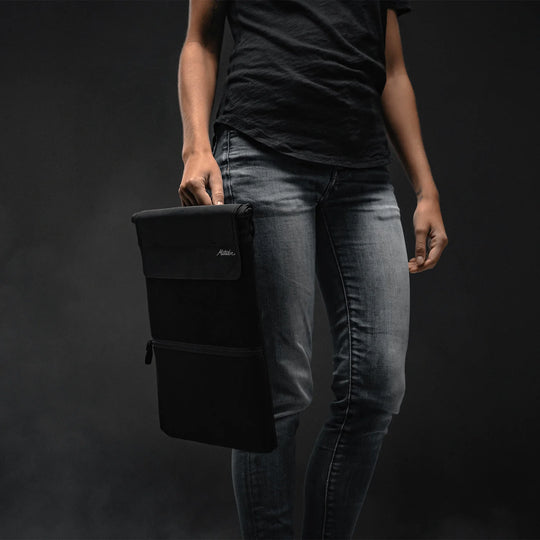 Person holding Laptop base layer by a carry handle