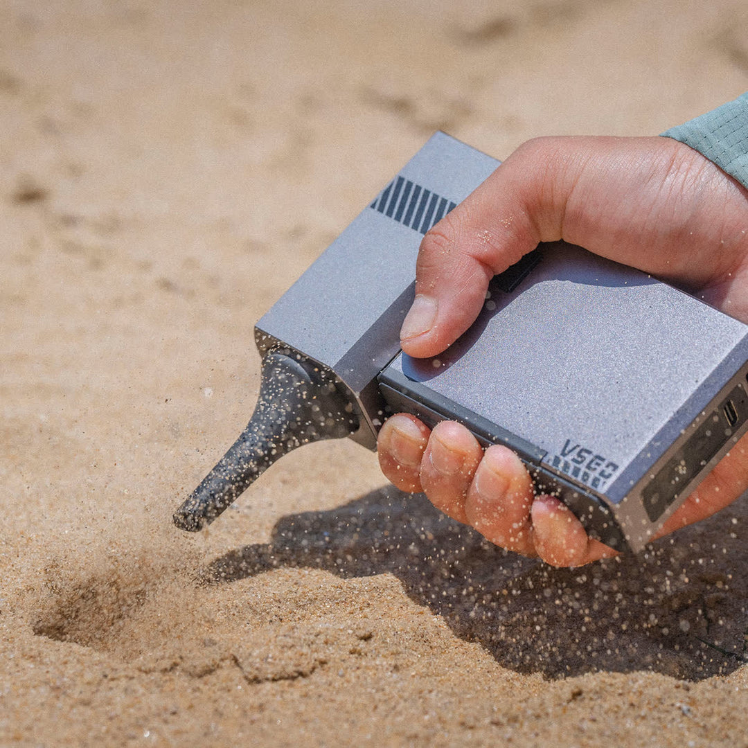 Hand holding a VSGO Pocket Beast Blower on sand