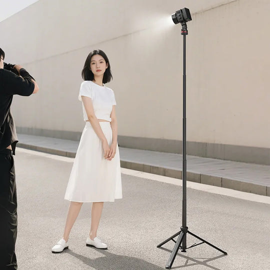 Woman in a white dress standing next to a camera on a tripod in an indoor setting