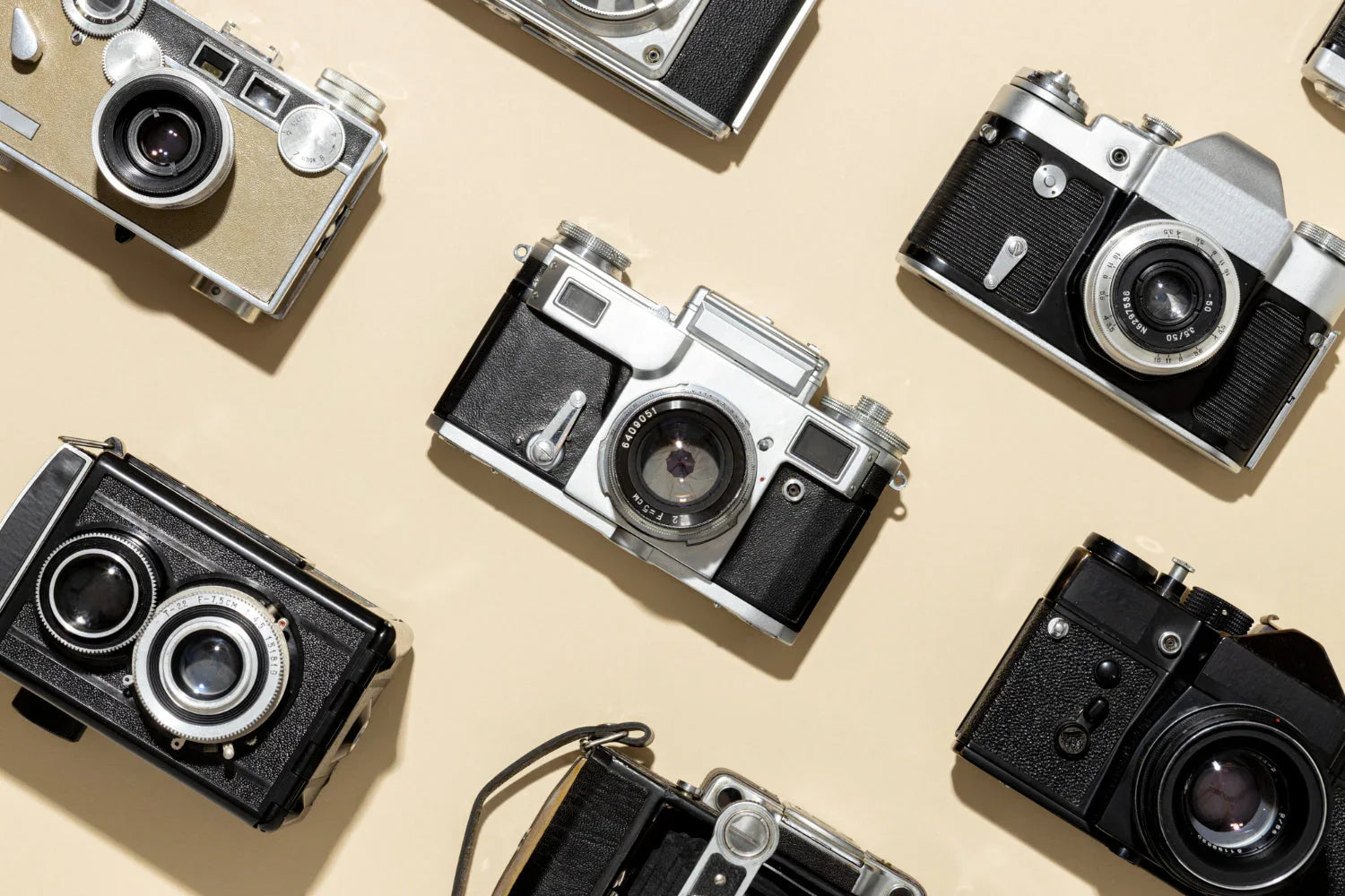 Assorted vintage film cameras displayed on a beige background for photography gear.