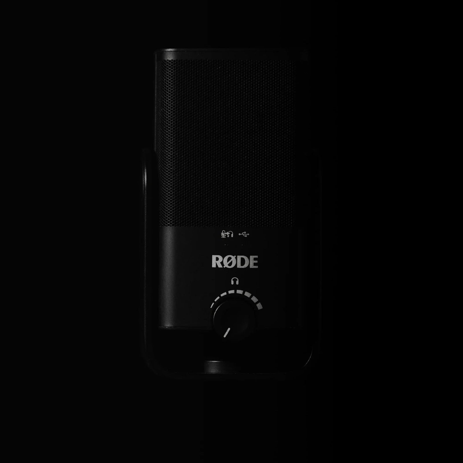 Rode condenser microphone with metal grille and control knob in dark studio lighting