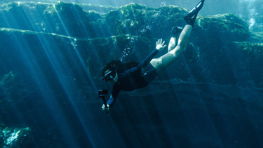 scuba diver exploring underwater scenery with sunlight filtering through water.