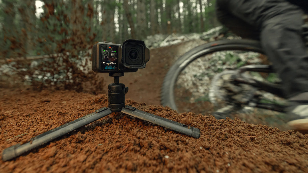 Camera on a tripod in a forest with a blurred cyclist in the background