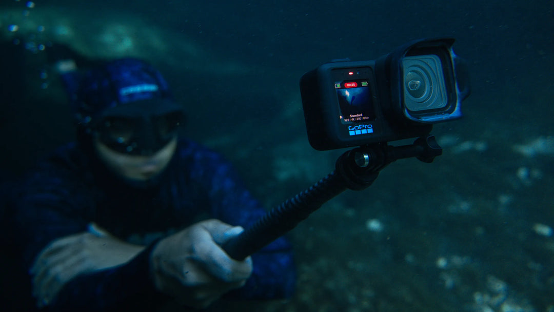 Person holding a GoPro camera underwater with a dark background
