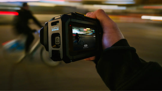 Hand holding a video camera with a blurred city street background