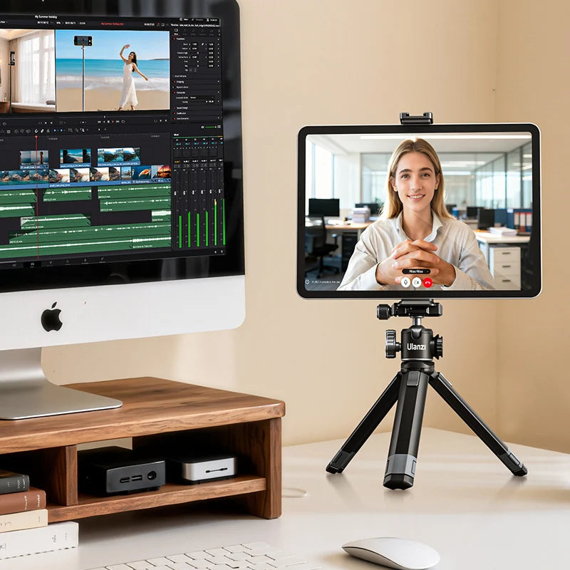 Video editing software on a computer monitor with a tablet displaying a video call on a tripod.