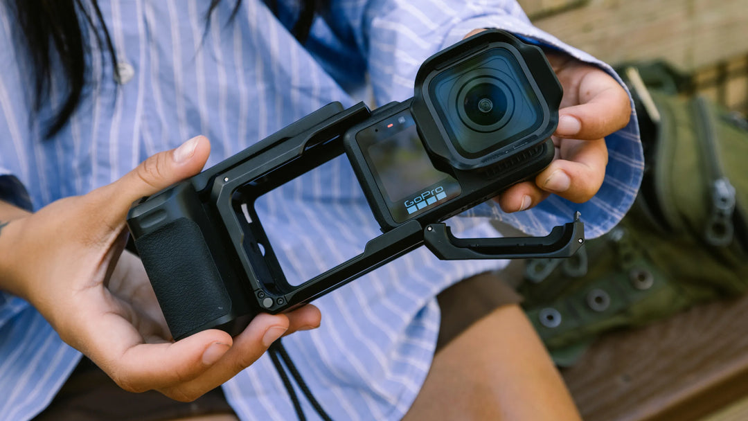 Person holding a camera with a mounted lens and screen protector