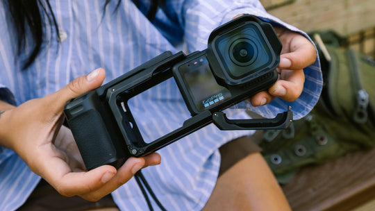 Person holding a camera with a mounted lens and screen protector