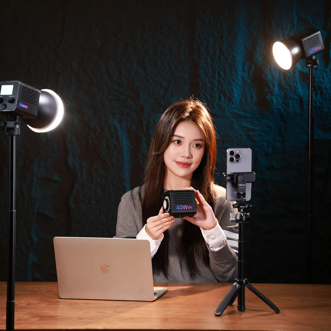 Woman holding a product in front of a camera setup with lighting equipment.