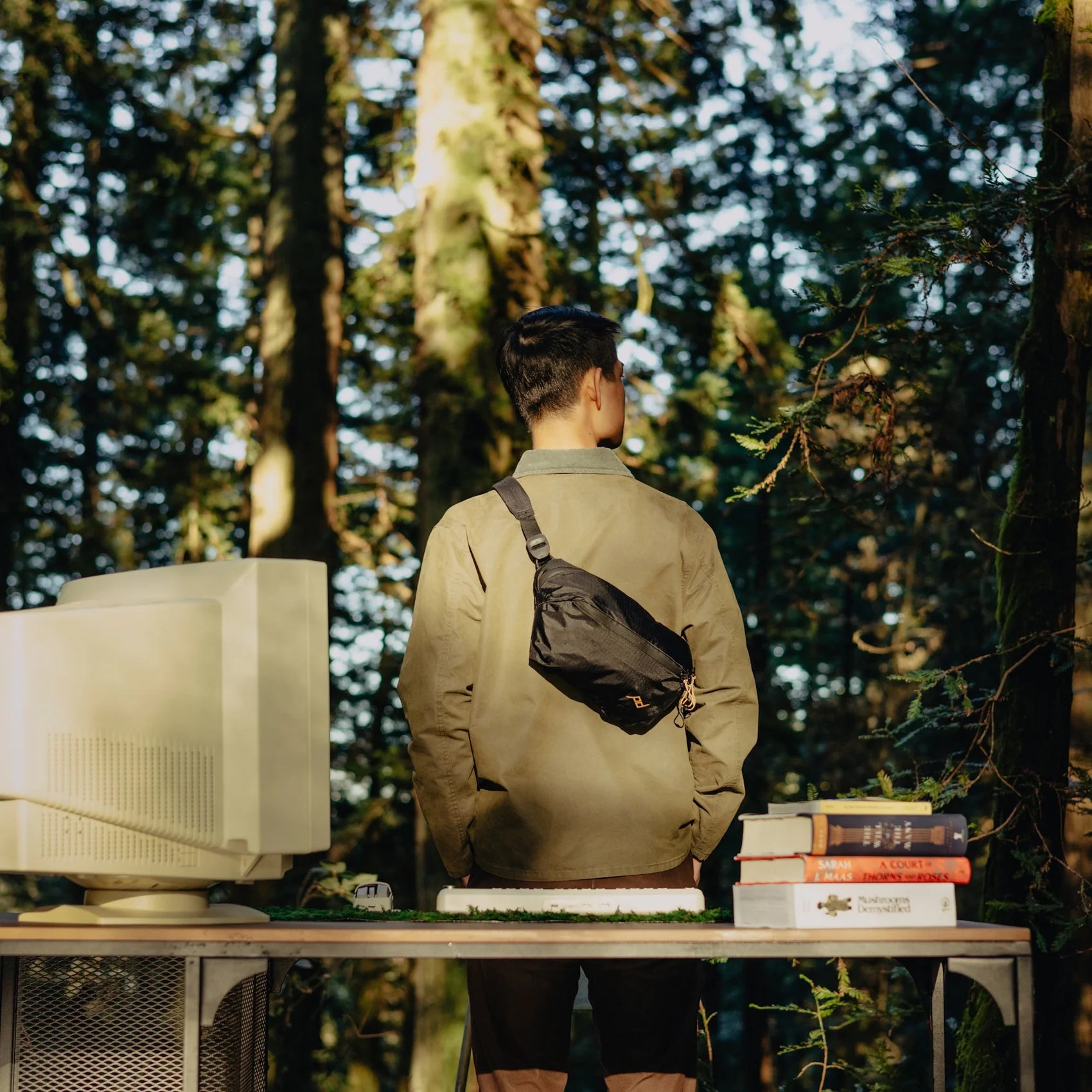 Person standing in a forest with a computer setup on a table