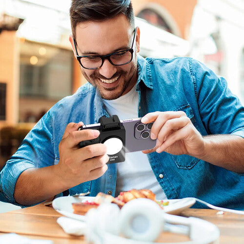 Man using a smartphone with a camera attachment in an outdoor setting