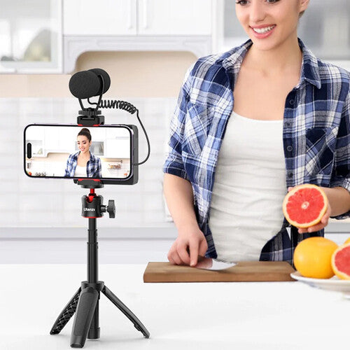 Person using a smartphone with a mounted camera and tripod in a kitchen setting.