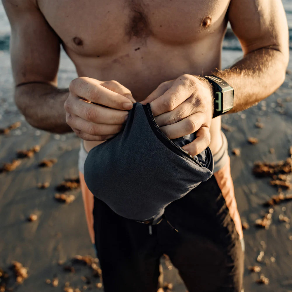 Man on a beach wearing a black glove and watch, with a blurred background.