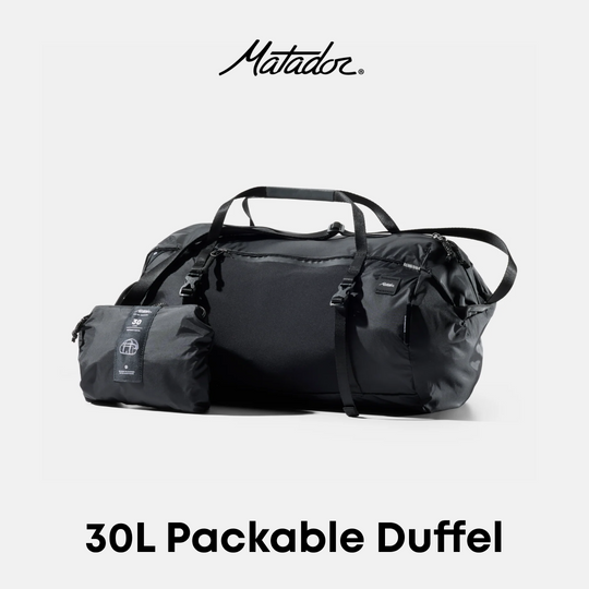 A black Matador 30L packable duffel bag shown with its compact folded pouch beside it on a light gray background, with the Matador logo at the top and &