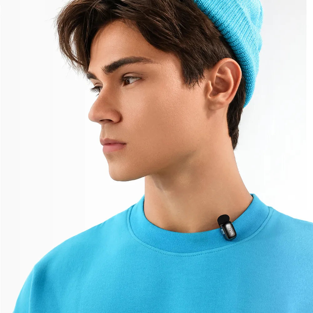 Person wearing a blue beanie and shirt with a small black device on a white background