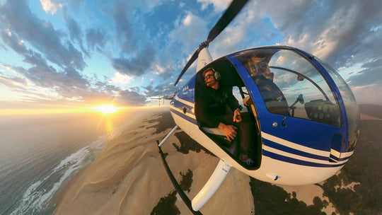 Helicopter flying over a beach with a sunset in the background