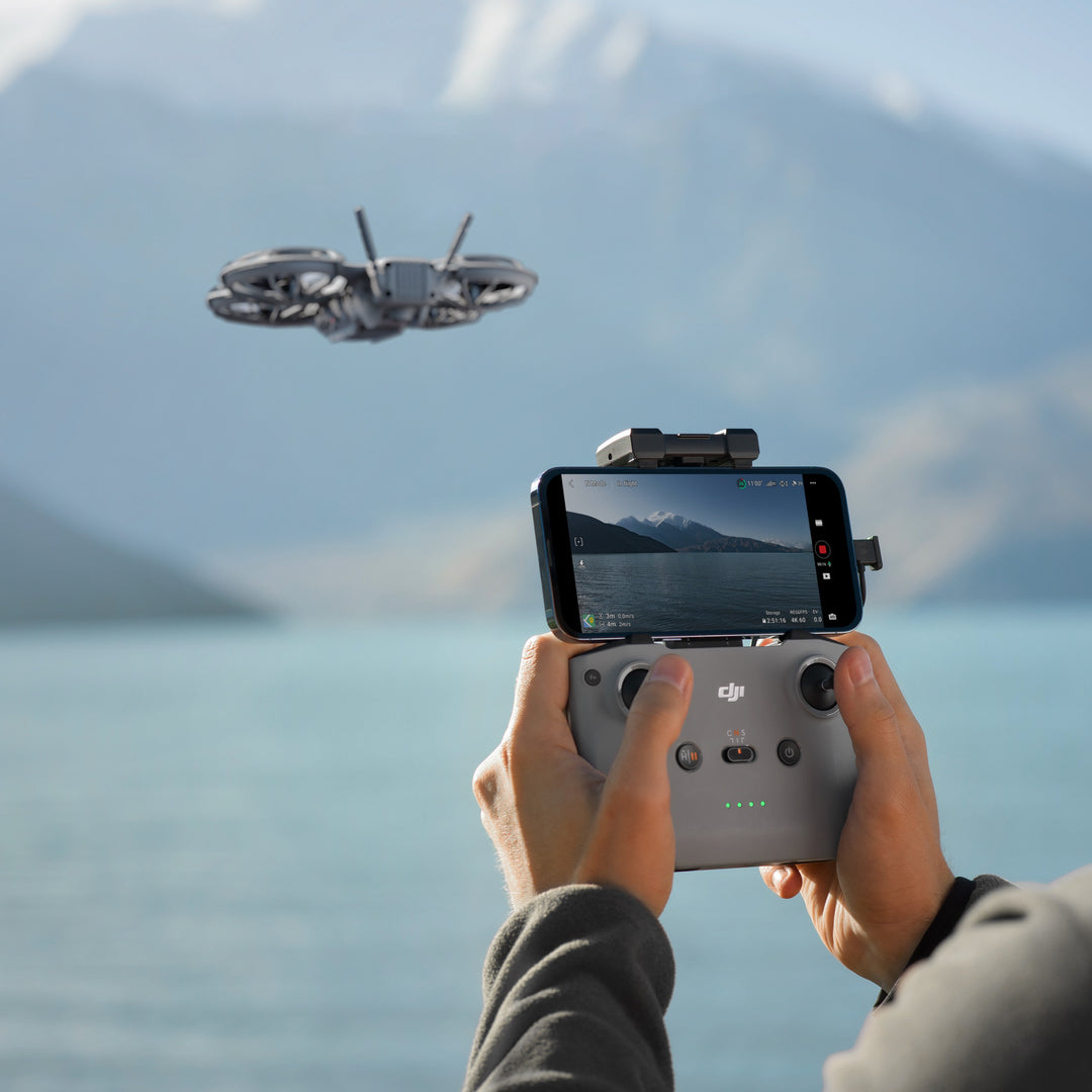 Person controlling a drone with a smartphone displaying a scenic view of mountains.