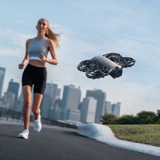 Woman running on a path with a drone flying above her in an urban setting
