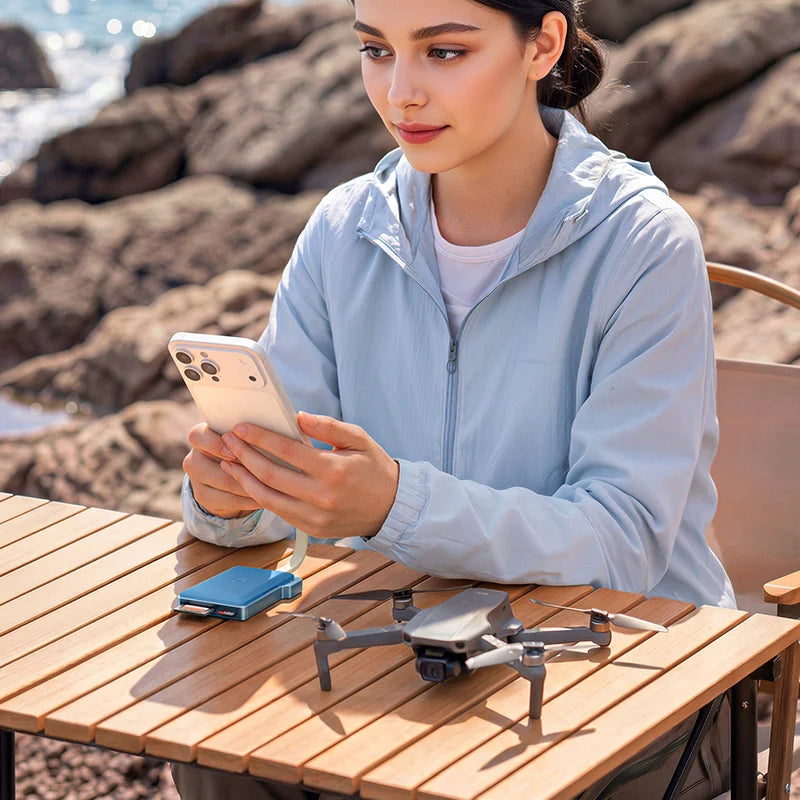 Woman using a smartphone with a drone on a wooden table by the sea.