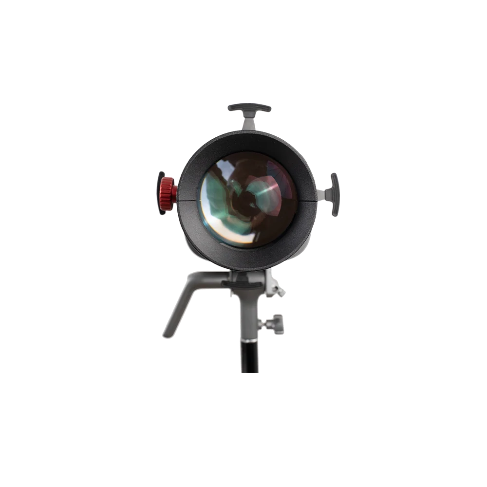 A studio light modifier or reflector head with a large circular glass lens, black metal body, side adjustment knobs, and a support stand, isolated on a white background.