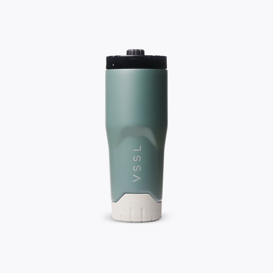 A VSSL insulated travel tumbler in a muted sage green color, featuring a black lid and a textured off-white base, shown on a clean white background.