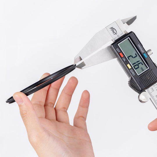 A hand holds a black magnetic adapter ring while a digital caliper measures its width against a clean white background.