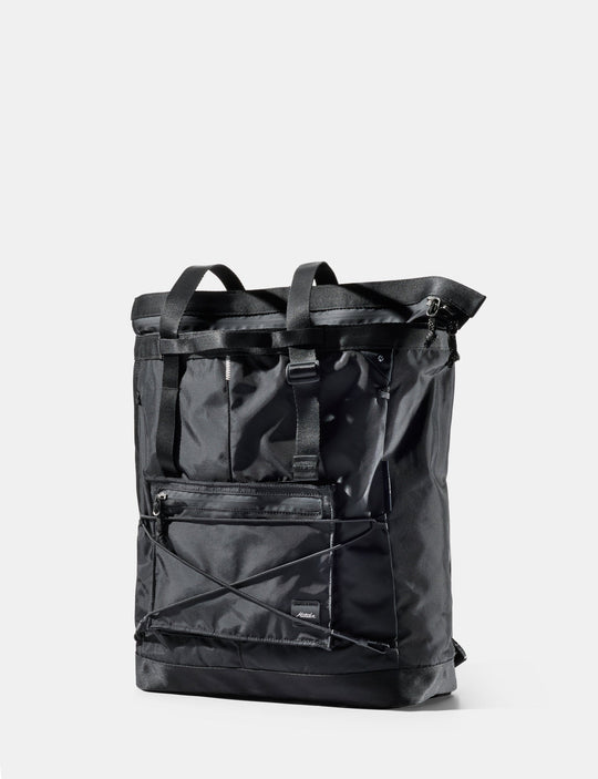 A black waterproof roll-top backpack with multiple front utility pockets, shown on a light gray background.