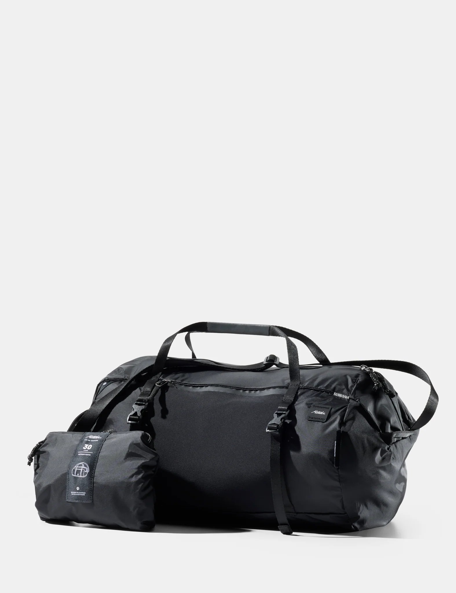 A black Matador 30L packable duffel bag shown with its compact folded pouch beside it on a light gray background, with the Matador logo at the top and '30L Packable Duffel' text at the bottom.