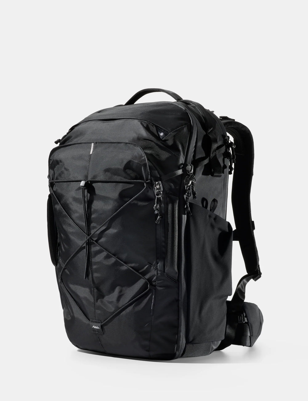 A black technical backpack with multiple zippered compartments, compression straps, and padded shoulder straps, shown from a three-quarter angle on a light gray background.