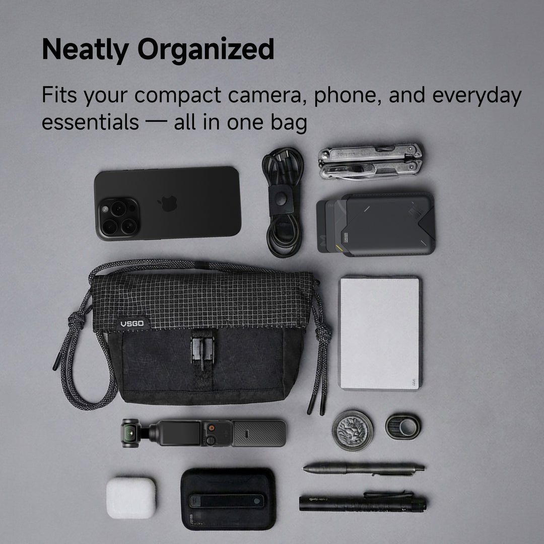 Black bag with various items including a phone, camera, and accessories on a gray background