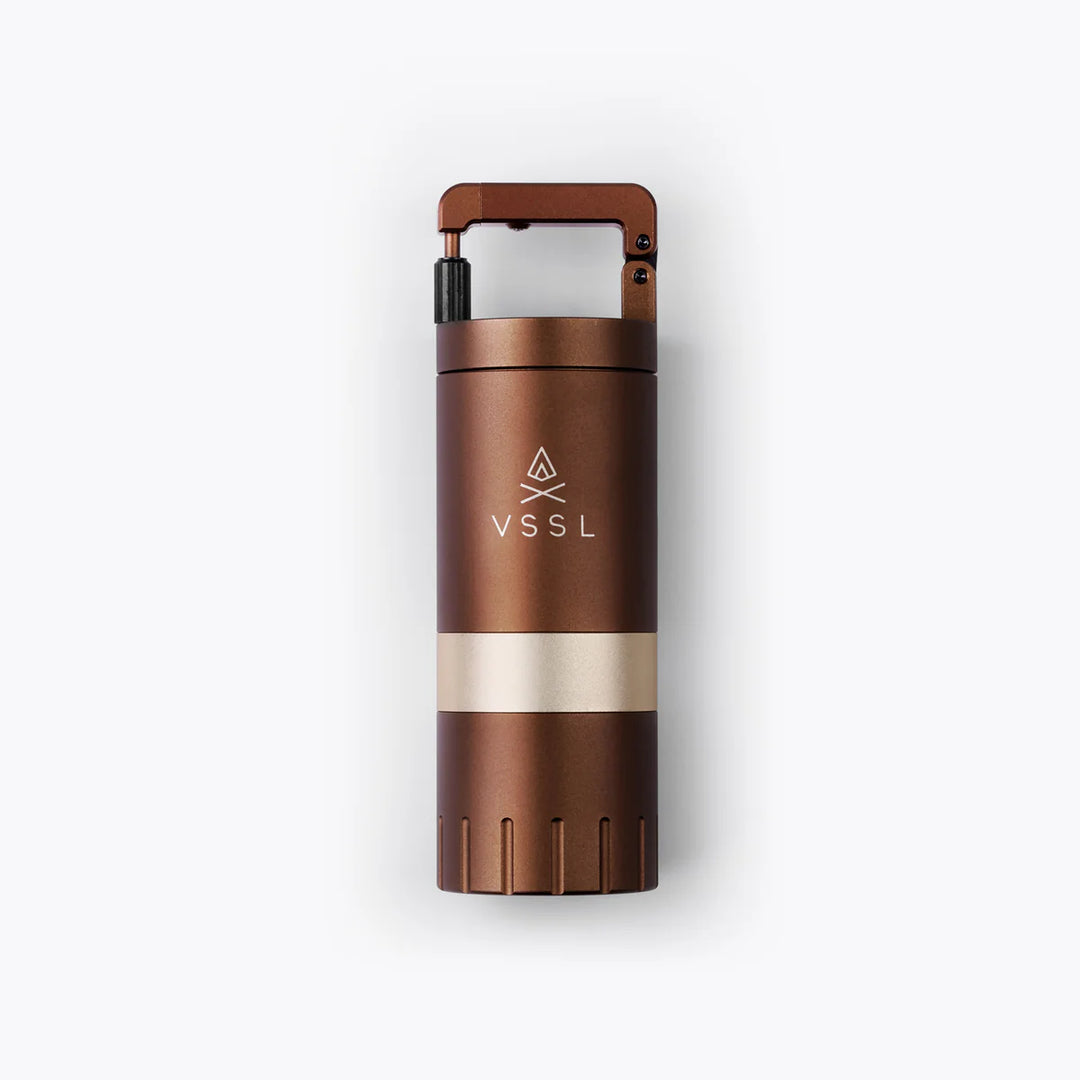 A VSSL portable camping stove component in a metallic bronze finish with a polished gold band and a black adjustment knob, shown on a clean white background.