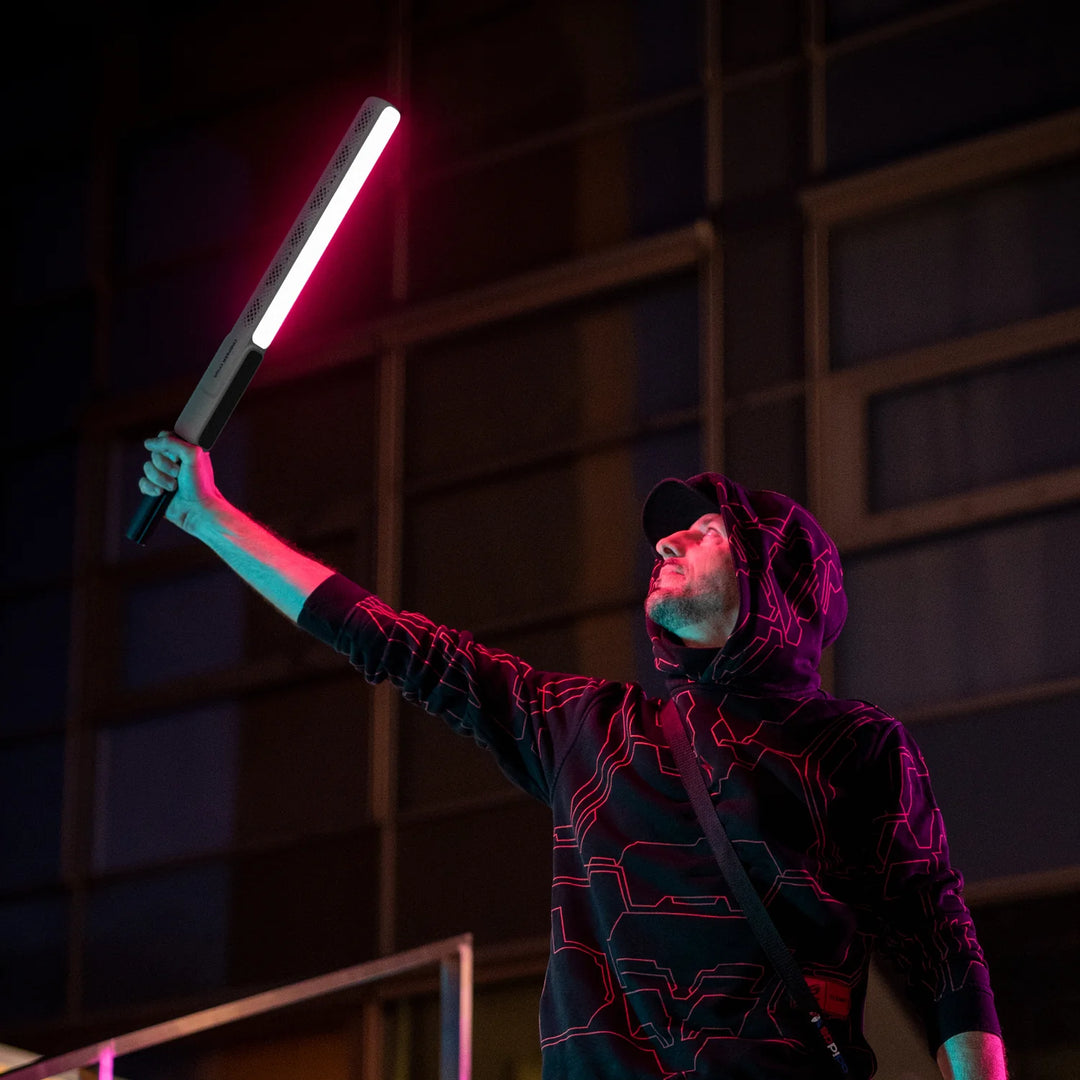 Person in a dark hoodie holding a glowing ZHIYUN CINEPEER CF100 LED Light Stick against a dark background