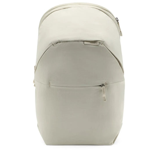 A light beige backpack with a front zippered pocket, shown from the back view against a plain white background.