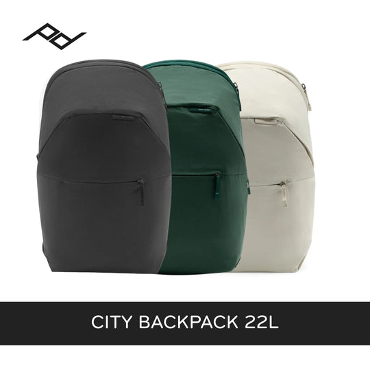 Three backpacks shown side by side on a white background: a black one in front, a dark green one in the middle, and a light beige/cream one behind. A black brand logo appears in the top left, and a black banner at the bottom reads &