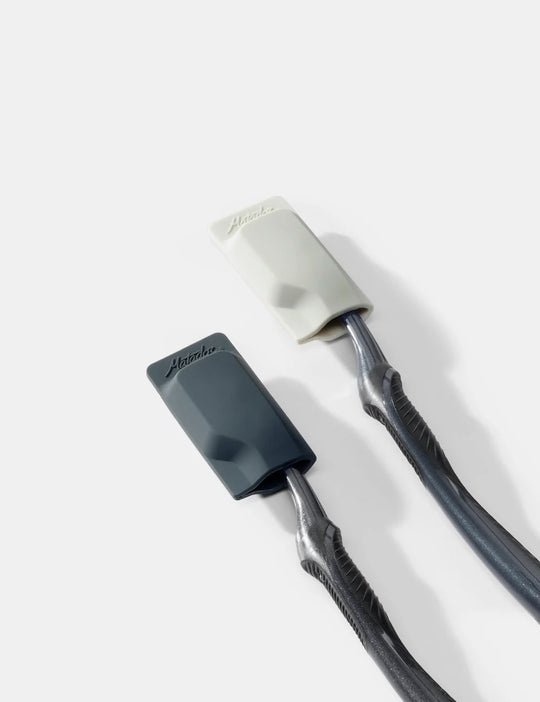 Close-up of a black and gray toothbrush with a white cover on a light gray background