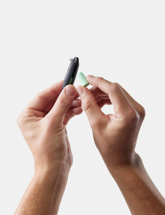Close-up of hands holding a small matador earplugs kit against a white background