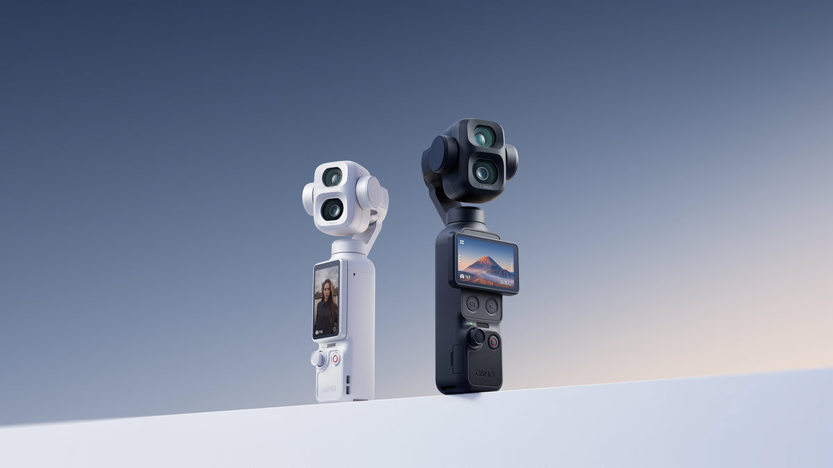 Two handheld action cameras, one white and one black, standing upright on a white surface against a blue gradient background. Both cameras feature dual lenses, a small rear screen, and a vertical grip.