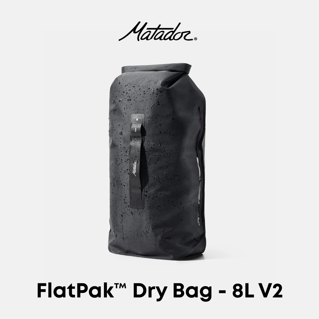 Matador FlatPak Dry Bag 8L V2 in black, shown standing upright against a light gray background with water droplets on its surface. The Matador logo is displayed at the top, and &