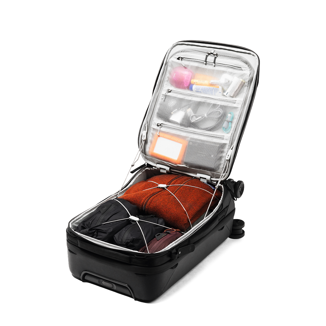 Open suitcase with compartments containing clothes and items on a white background