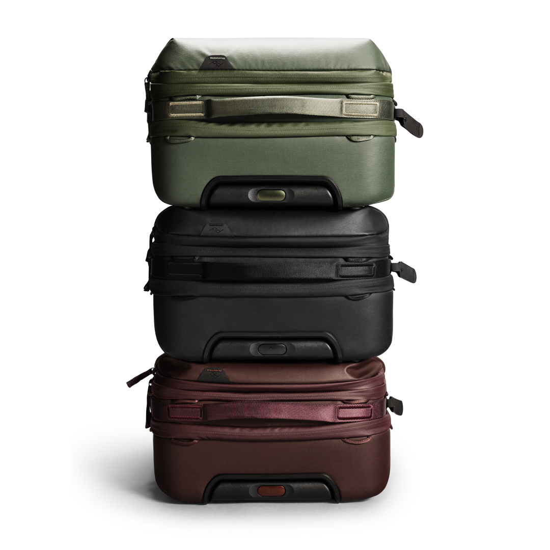 Stack of three suitcases in green, black, and brown on a white background